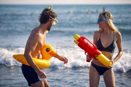 Foto de Jóvenes felices con juguetes acuáticos se divierten en la playa junto al mar - Imagen libre de derechos