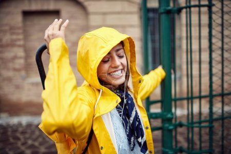 Photo for Cheerful girl in yellow raincoat enjoying outdoor - Royalty Free Image