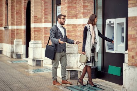 Photo for Man and woman standing in front of cash machine - Royalty Free Image