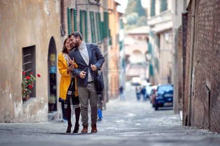 Photo for A young couple in love is enjoying emotional moments while walking the old city in a relaxed manner. Walk, rain, city, relationship - Royalty Free Image