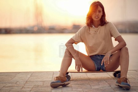 Téléchargez les photos : Jeune femme à la mode chevauchant le skateboard par une journée ensoleillée - en image libre de droit