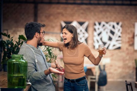 Téléchargez les photos : Jeune couple dans un bar se disputant. Femme en colère contre l'homme et tenant sa bouche fermée. - en image libre de droit
