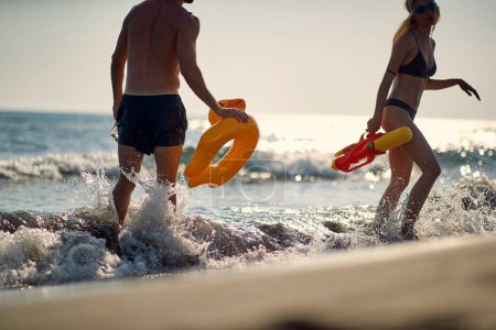 Foto de Una joven pareja disfruta jugando con juguetes en la playa en un hermoso día de verano. Verano, playa, mar, vacaciones - Imagen libre de derechos