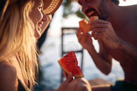 Foto de Primer plano retrato de pareja disfrutando de la fruta del melón juntos. Vacaciones de verano por mar. Vacaciones, unión, concepto de estilo de vida. - Imagen libre de derechos