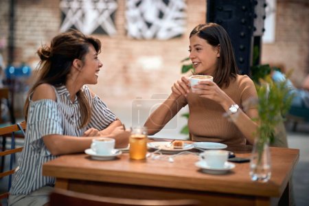 Foto de Mujeres jóvenes hipster tomando café juntas, en el café en el interior. Diversión, unión, concepto de estilo de vida. - Imagen libre de derechos