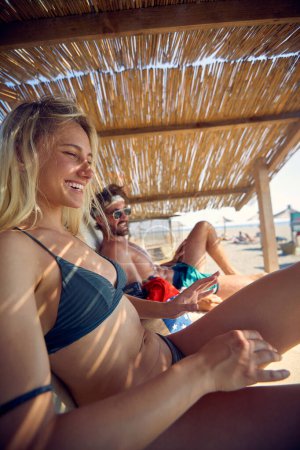 Photo for Smiling couple sunbathing on a beach and enjoying at summer vacation. - Royalty Free Image