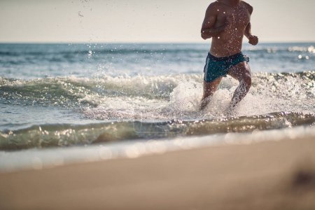 Téléchargez les photos : Musclé beau homme courir dans l'eau, goutte d'eau brillant - en image libre de droit