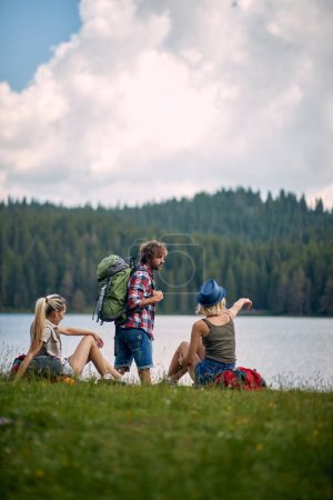 Téléchargez les photos : Jeunes amis avec sacs à dos regarder beau lac à la randonnée - en image libre de droit