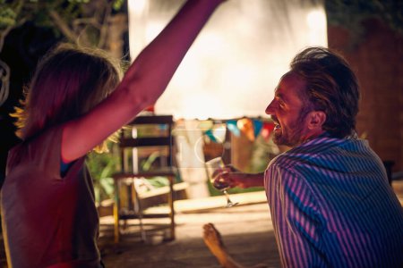 Téléchargez les photos : Un jeune couple bavardant tout en profitant d'une soirée au bar au bord de la rivière par une belle nuit d'été. Nuit, été, bar, rivière - en image libre de droit