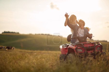 Téléchargez les photos : Beaux jeunes mariés conduite quad ensemble dans la nature ; Concept de mariage rural - en image libre de droit