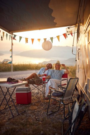 Foto de Pareja sonriente divirtiéndose al aire libre.Alegre hombre y mujer de fiesta cerca de Camper Van moderna en el camping - Imagen libre de derechos