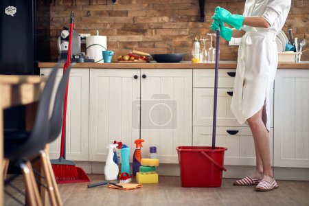 Téléchargez les photos : Outils de nettoyage essentiels : une serpillière, un seau rempli d'eau et la résolution inébranlable d'une femme. - en image libre de droit