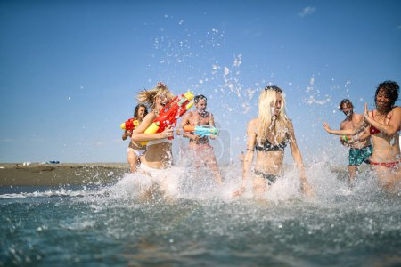 Foto de Un grupo de amigos se está divirtiendo mientras juega en el agua en la playa en un hermoso día de verano. Verano, playa, mar, vacaciones - Imagen libre de derechos