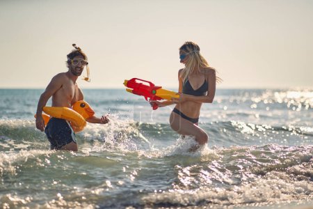 Photo for Two friends having a water gun fight on the beach - Royalty Free Image