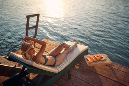 Téléchargez les photos : Belle blonde profitant du bain de soleil sur la plage - en image libre de droit