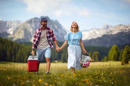 Photo for Young cheerful smiling couple in love holding hands and walking in nature on a beautiful  day. - Royalty Free Image