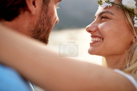 Téléchargez les photos : Gros plan portrait de mariée joyeuse avec un grand sourire regardant son mari. Couple en bord de mer. Mariage, lune de miel, concept d'amour - en image libre de droit