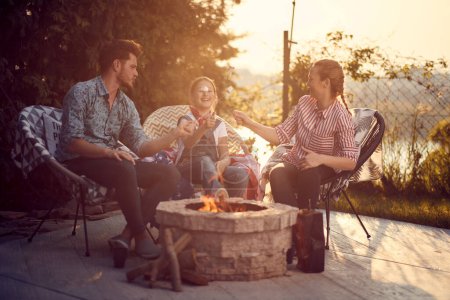 Photo for Mom, dad and daughter being silly, roasting marshmallows outdoors by fireplace, enjoying sunny summer day together. Togetherness, family, lifestyle concept. - Royalty Free Image