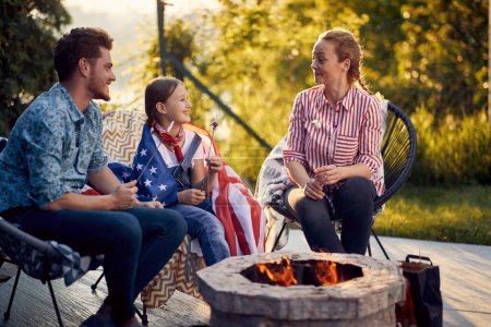 Photo for Lovely family roasting marshmallows by fireplace. Mom dad and daughter enjoying sunny summer day together. Lifestyle, togetherness, family concept. - Royalty Free Image
