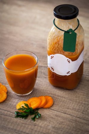 Foto de Jugo de zanahoria exprimido saludable en tabl de madera - Imagen libre de derechos