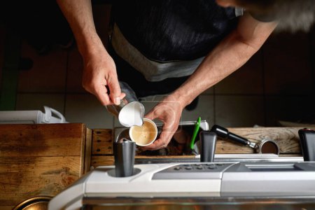Foto de Detalle de la vista superior del hombre caucásico vertiendo leche en una taza de café - Imagen libre de derechos