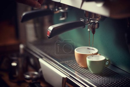 Foto de Enfoque selectivo del dispositivo de café expreso, vertiendo chorro de café en dos tazas. naranja y verde. - Imagen libre de derechos