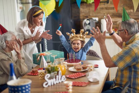 Photo for A heartwarming family celebration unfolds as a little girl joyfully celebrates her birthday surrounded by her parents, grandparents, and a beautifully decorated birthday cake. - Royalty Free Image