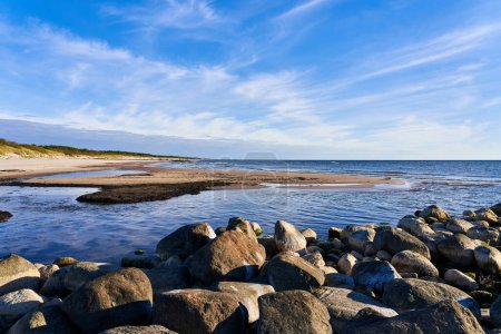 Un grand tas de pierres se trouve près du bord de la mer. Un vieux brise-lames en pierre ou une jetée à marée basse