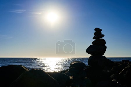 Eine kleine Rutsche aus Steinen vor blauem, gesättigtem Meer und Himmel. Ein Bild für die Meditation
