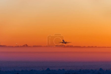 Das Flugzeug landet im Morgengrauen bei dichtem Nebel. Die Silhouette eines Flugzeugs gegen den Himmel