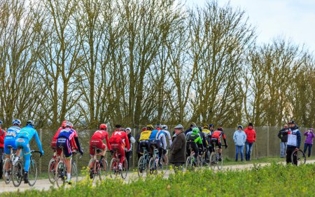 Photo for Vendome,France- March 7,2016:The cyclists rinding in the peloton on a dirty road,Tertre de la Motte, in Vendome, during the first stage of Paris-Nice 2016. - Royalty Free Image