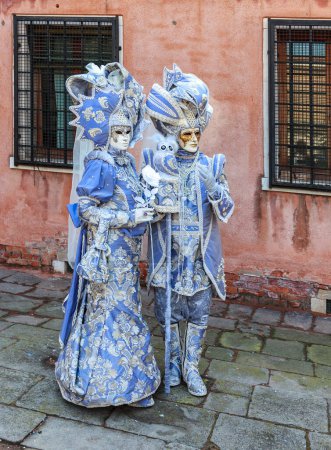Téléchargez les photos : Venice, Italy- February 18, 2012: Environmental portrait of couple disgused in a beautiful old-fashioned style costume posing in a small Venetian sqaure during the Venice Carnival days - en image libre de droit