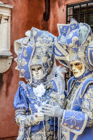 Photo for Venice, Italy- February 18, 2012: Environmental portrait of couple disgused in a beautiful old-fashioned style costume posing in a small Venetian sqaure during the Venice Carnival days - Royalty Free Image