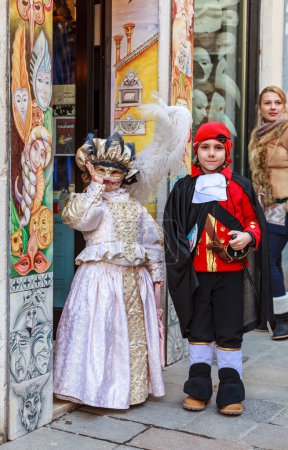 Téléchargez les photos : Venise, Italie- 18 février 2012 : Image d'un couple d'enfants déguisés posant devant une boutique traditionnelle, pendant le Carnaval de Venise - en image libre de droit