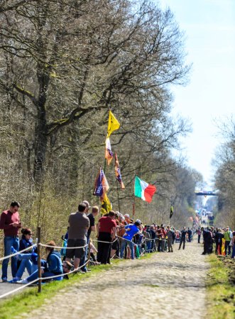 Foto de Wallers-Arenberg, Francia - 12 de abril de 2015: Espectadores esperando el pelotón en el famoso sector pavimentado, The Arenberg gap (Trouee d 'Arenberg), antes del paso de los ciclistas durante la carrera ciclista París-Roubaix. - Imagen libre de derechos