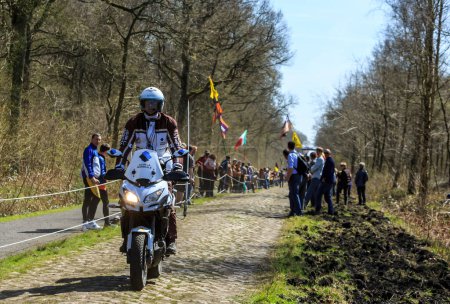Foto de Wallers-Arenberg, Francia - 12 de abril de 2015: La bicicleta oficial AG2R La Mondiale conduce en el famoso sector pavimentado, The Arenberg gap (Trouee d 'Arenberg), antes del paso de los ciclistas durante la carrera ciclista París-Roubaix. - Imagen libre de derechos