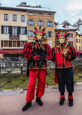 Téléchargez les photos : Annecy, France, February 24, 2013: A couple of unidentified persons disguised in red jester costumes poses near a canal in Annecy during a Venetian Carnival, which celebrates the beauty of the real Venice - en image libre de droit