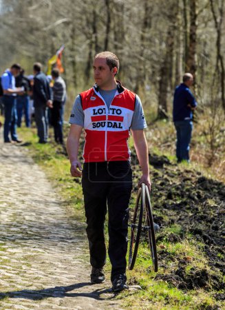 Foto de Wallers-Arenberg, Francia - 12 de abril de 2015: Imagen de un mecánico de apoyo de equipo con dos ruedas de repuesto en el famoso sector pavimentado, The Arenberg gap (Trouee d 'Arenberg), durante la carrera ciclista París-Roubaix. - Imagen libre de derechos