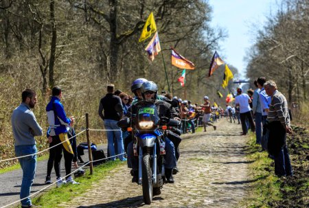 Foto de Wallers-Arenberg, Francia - 12 de abril de 2015: La bicicleta oficial de un fotógrafo conduce por el famoso sector pavimentado, The Arenberg gap (Trouee d 'Arenberg), antes del paso de los ciclistas durante la carrera ciclista París-Roubaix. - Imagen libre de derechos