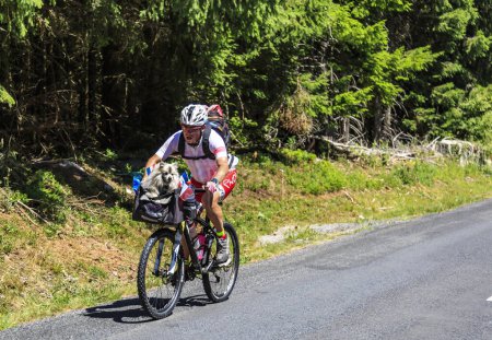 Téléchargez les photos : Côte de la Fage, France - 16 juillet 2022 : Un cycliste amateur non identifié et son chien roulent sur la route sur la Côte de la Fage dans les monts Cévennes lors de l'étape 14 du Tour de France 2022 - en image libre de droit