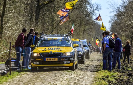 Téléchargez les photos : Wallers-Arenberg, France - 12 avril 2015 : La voiture de Lotto-Jumbo Team roule sur le fameux secteur pavé, The Arenberg gap (Trouee d'Arenberg), avant le passage des cyclistes lors de la course cycliste Paris-Roubaix. - en image libre de droit