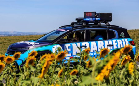 Photo for Villefranche-d'Albigeois, France - July 17th, 2022: Image of the car of gendarmerie driving in the Publicity Caravan, near a field of sunflowers during the stage 15 of Le Tour de France 2022 - Royalty Free Image