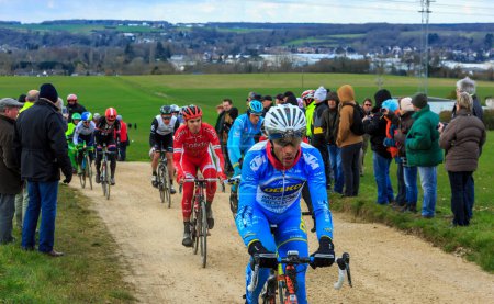 Photo for Vendome,France- March 7,2016:The cyclists rinding in the peloton on a dirty road,Tertre de la Motte, in Vendome, during the first stage of Paris-Nice 2016. - Royalty Free Image