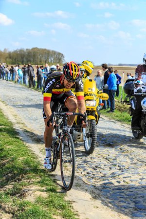 Foto de Carrefour de l 'Arbre, Francia - 12 de abril de 2015: El ciclista belga, Stig Broeckx del equipo Lotto Soudal, monta en el pelotón en el famoso sector Careffour de l' Arbre durante la carrera París-Roubaix en 2015. - Imagen libre de derechos