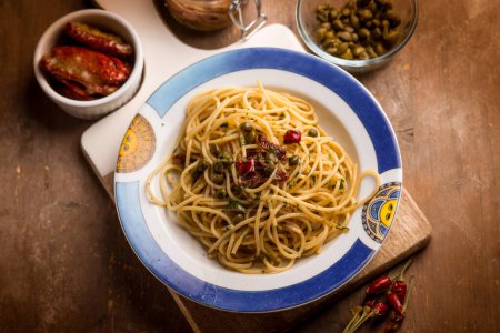 Foto de Espaguetis con anchoas tomates secos y alcaparras - Imagen libre de derechos
