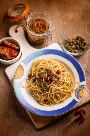 Foto de Espaguetis con anchoas tomates secos y alcaparras - Imagen libre de derechos