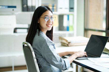 Photo for Smiling asian business woman online working on laptop at home office. Young girl asian student or remote teacher using computer online studying, virtual training, watching online education webinar at home office. - Royalty Free Image