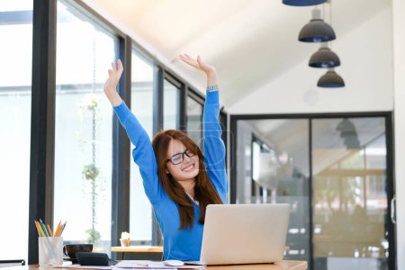 Young Asian woman excited by good news celebrate success or happy pose with laptop.