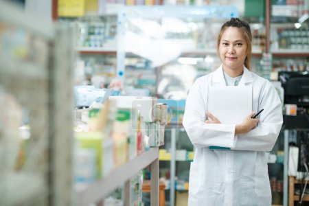 Photo for Portrait of young professional female pharmacist in white gown standing in drugstore with clipboard prepared and happy to give clients recommendations, suggestions, and prescribed medicarions. Medicine, pharmacy, healthcare concept. - Royalty Free Image