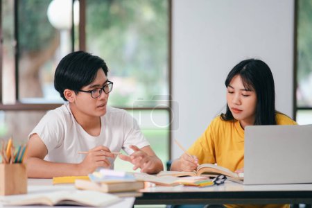 Photo for Young asian university students are studying for an exam. There are tutor books with friends. They are classmates that try to help each other. They have been tutoring for many hours in the campus. - Royalty Free Image